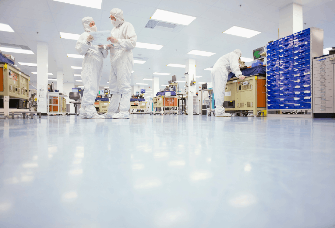 Scientists in safety suits talking in a lab where a hygienic flooring system has been implemented.